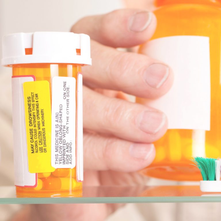 a hand reaching for prescription pill bottle as header for opioid safety section