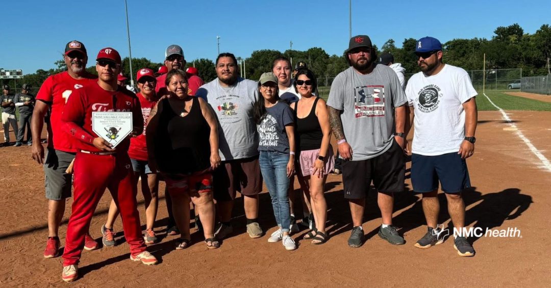 group of family members standing on baseball diamond giving award to player