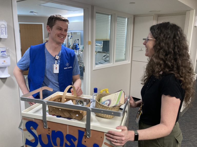 young man and woman standing over a cart in the hospital smiling