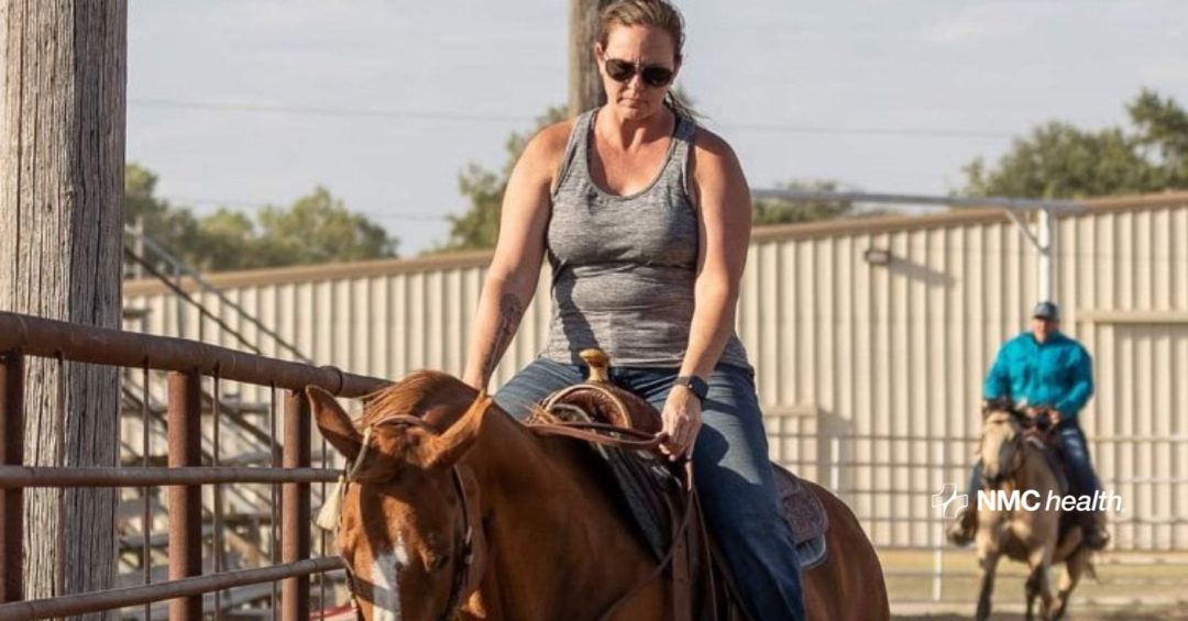 woman wearing gray tank top and sunglasses riding a brown horse