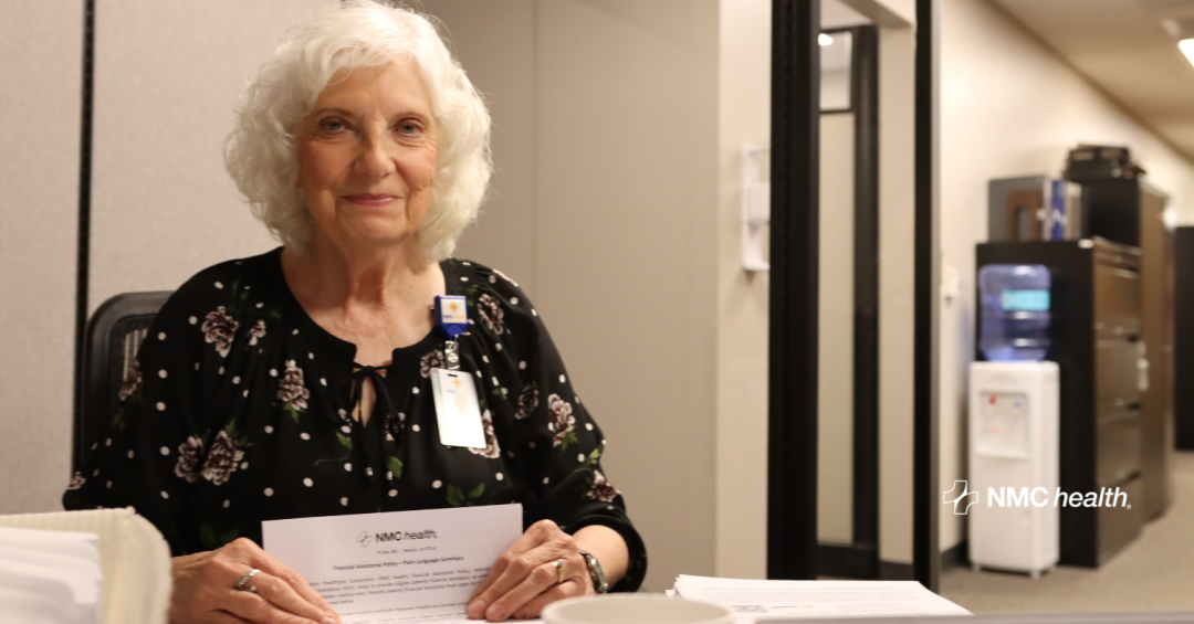 older woman smiling and looking forward while folding piece of paper