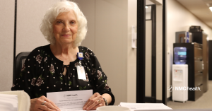 older woman smiling and looking forward while folding piece of paper