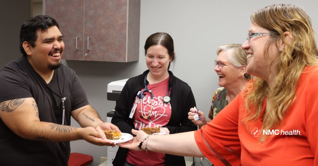 smiling woman handing plate of food to smiling man with others in the background