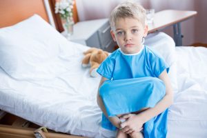 Little boy sitting on hospital bed and looking at camera