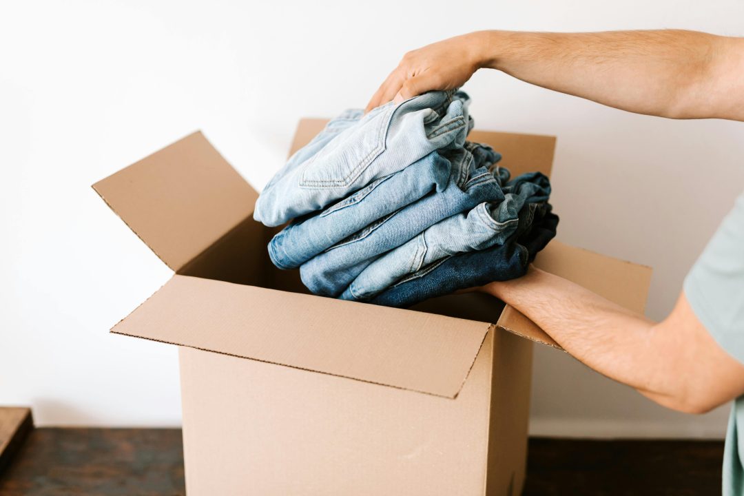 a person holding a pile of jeans in a box