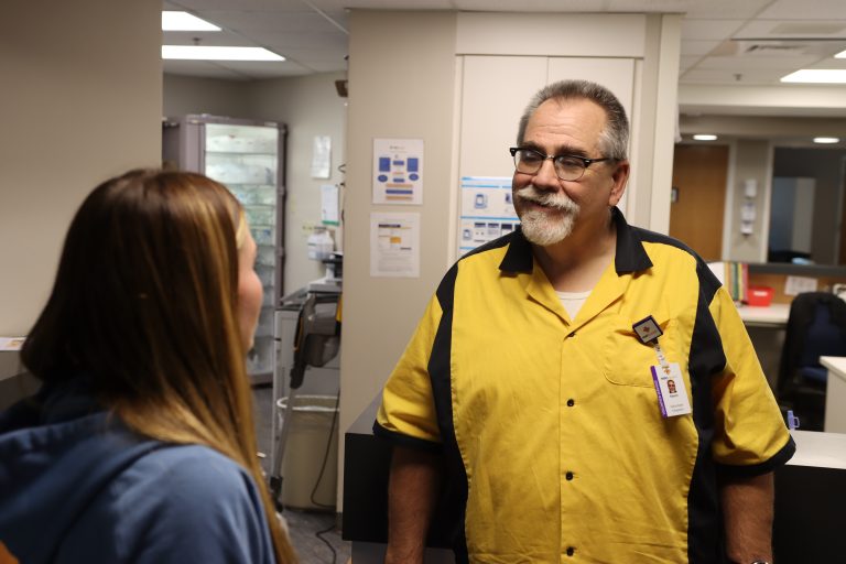 volunteer chaplain listening to nurse talking at hospital nurses station