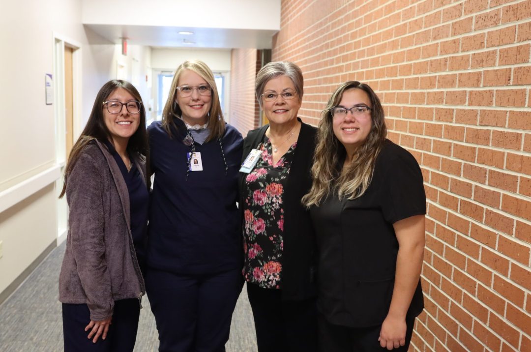 group of four women in healthcare smiling and looking at the camera