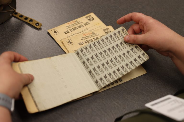 hands flipping through a WWII ration book