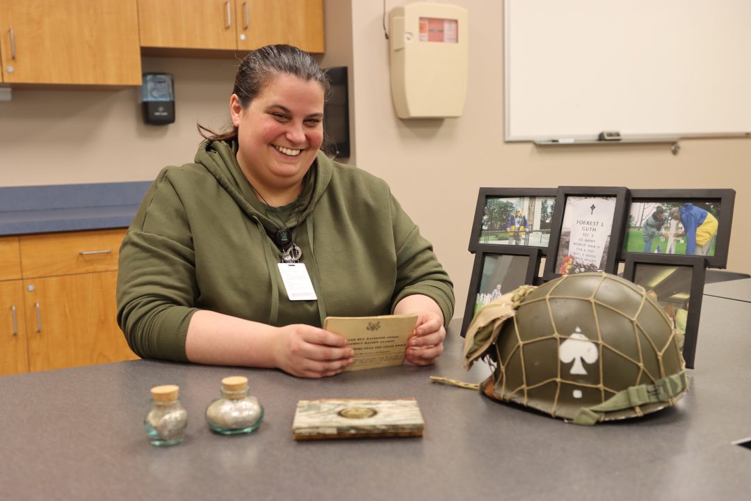 woman sitting at table surrounded by WWII memorabilia