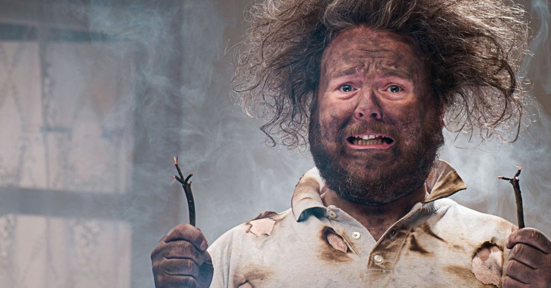 man with scorched fabric and singed hair, holding cut wires