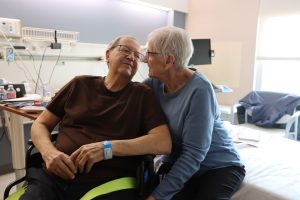 elderly man and woman looking at each other, smiling, in hospital room
