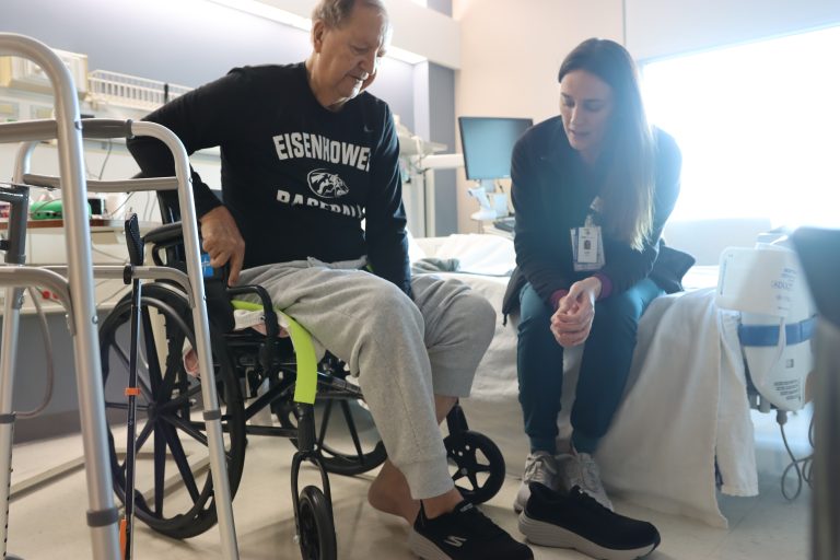a man in a wheelchair next to a woman learning how to put on a shoe, occupational therapy