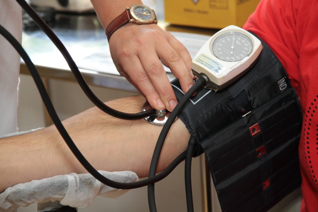 person having blood pressure taken at doctor's office, stethoscope