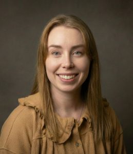 a woman with brown hair wearing a brown blouse sliming