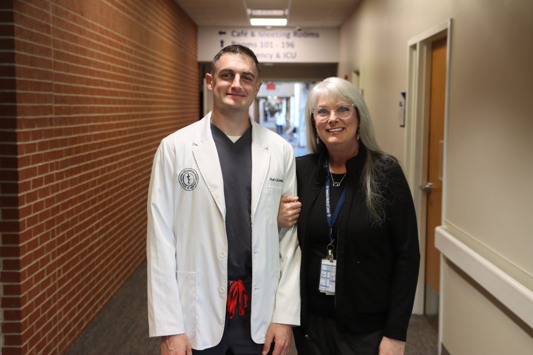 Two smiling people in a hospital corridor