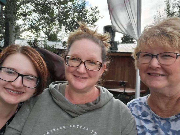Three women of different generations look at the camera and smile