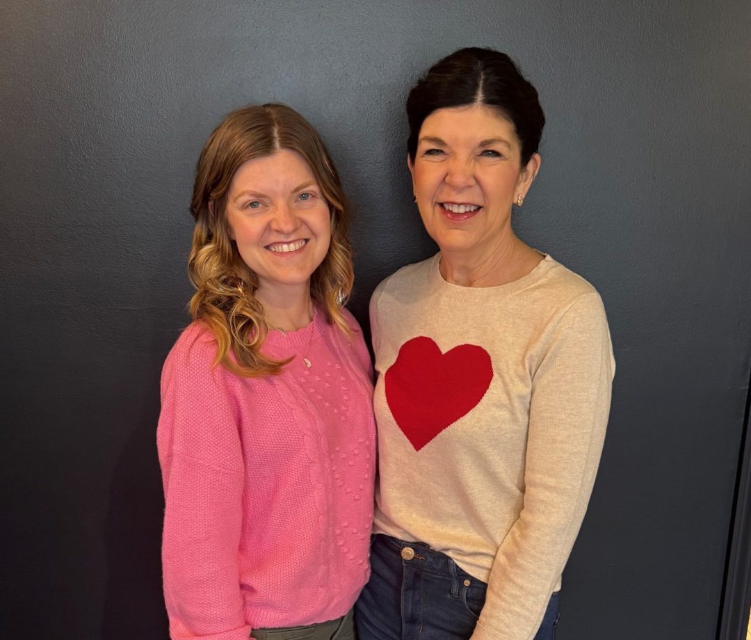 Two women standing against painted wall