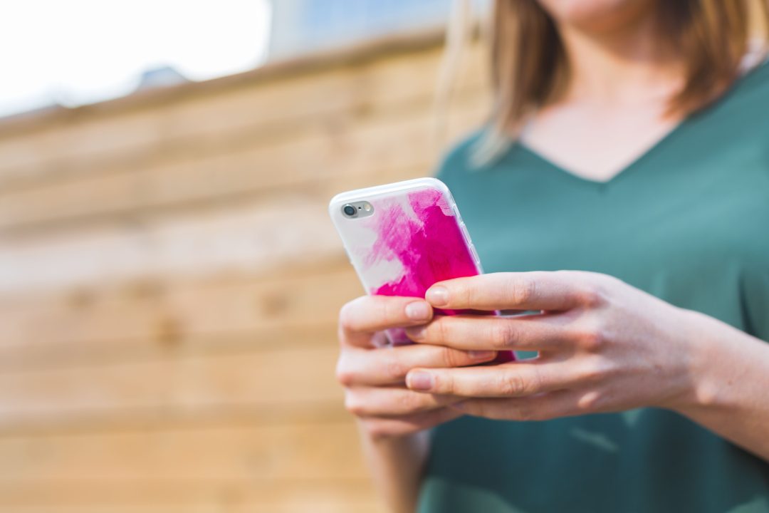 person wearing green shirt holding cell phone
