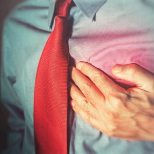 Heart Attack man in blue dress shirt with red tie clenching chest showing heart attack