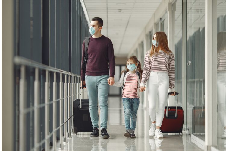 COVID Travel family walking through airport with masks on covid-19 vaccine travel after getting vaccine