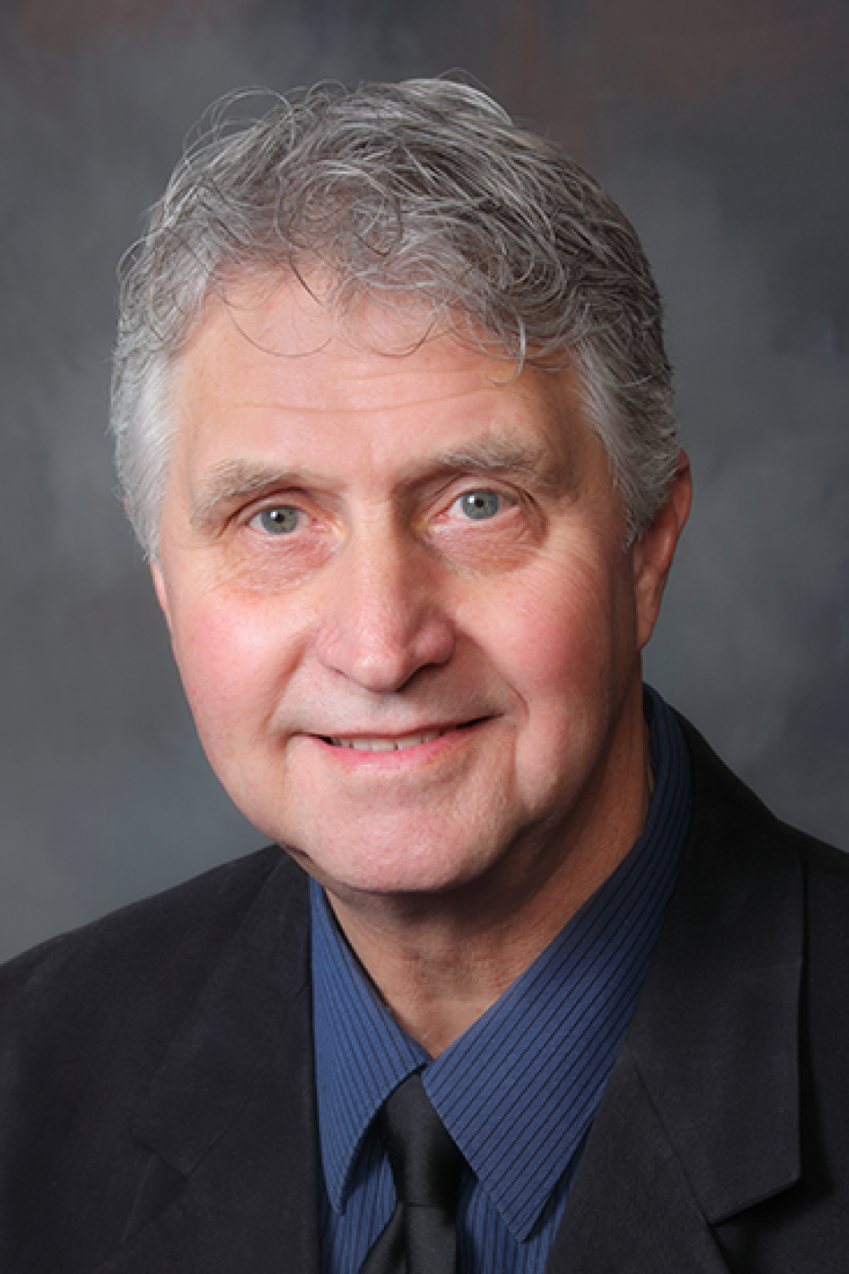 Dr. John Hart wearing suit and dark blue shirt - headshot